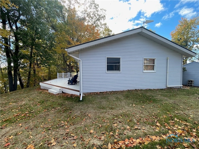 view of side of home featuring a wooden deck and a yard