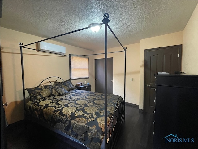 bedroom with a wall unit AC, a textured ceiling, and dark wood-type flooring