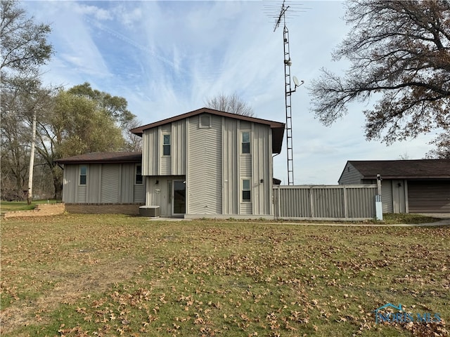 rear view of property featuring central AC unit and a lawn