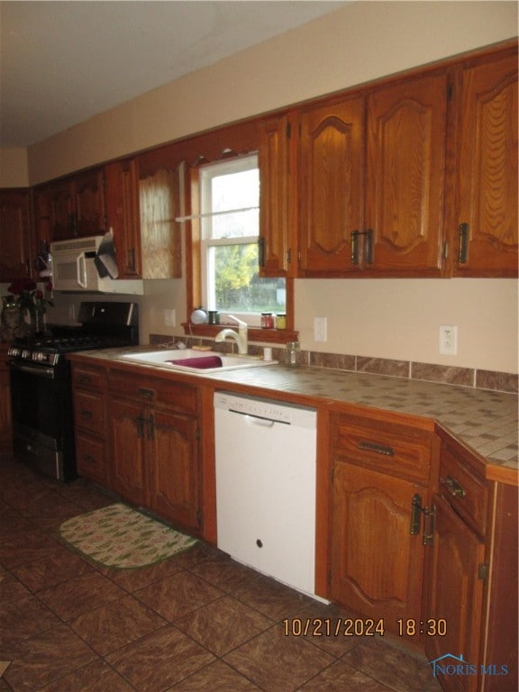 kitchen with sink, tile counters, white appliances, and dark tile patterned flooring