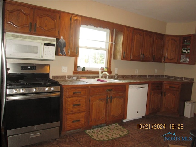 kitchen featuring white appliances, tile countertops, sink, and dark tile patterned flooring