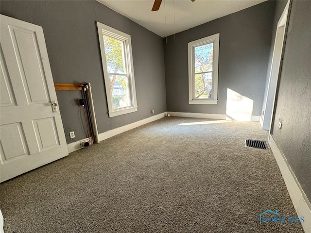 carpeted empty room featuring a healthy amount of sunlight and ceiling fan