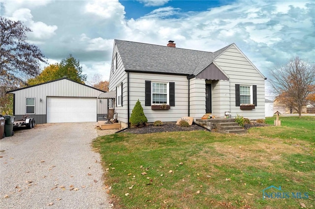 view of front of home with a garage, a front yard, and an outbuilding