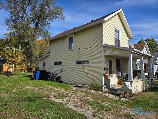 rear view of house featuring covered porch and a yard