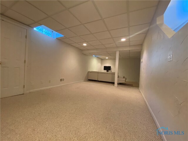 basement with a drop ceiling and light carpet