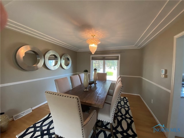 dining area with crown molding and hardwood / wood-style floors