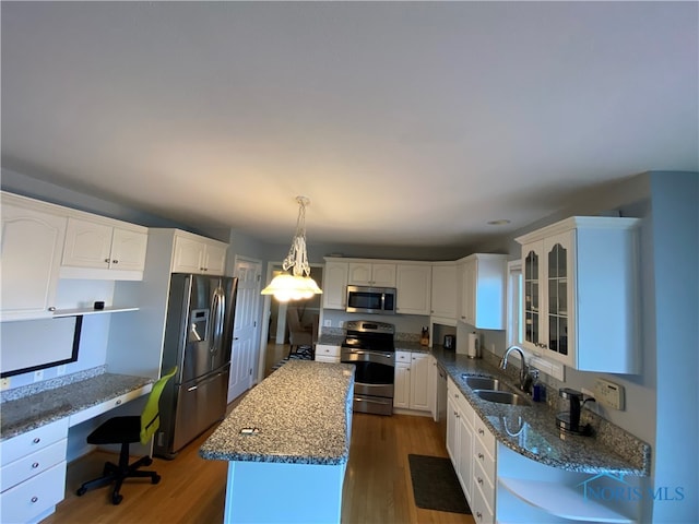 kitchen featuring dark wood-type flooring, a center island, stainless steel appliances, and sink