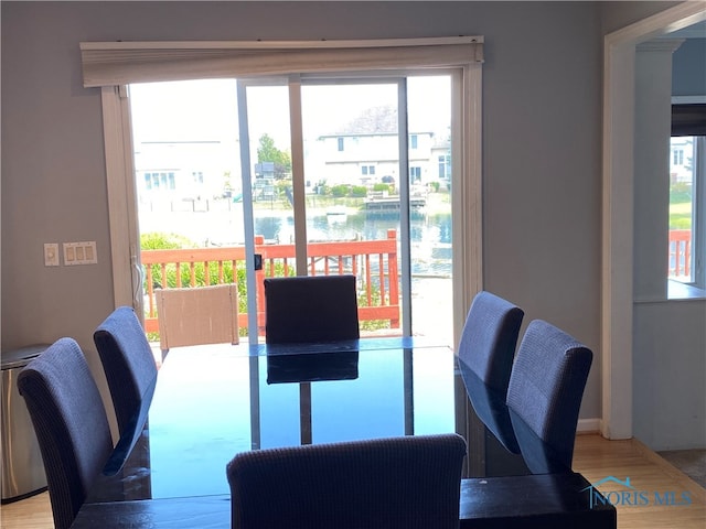 dining room featuring a water view, hardwood / wood-style flooring, and a healthy amount of sunlight