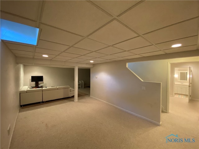 basement with a paneled ceiling and light colored carpet