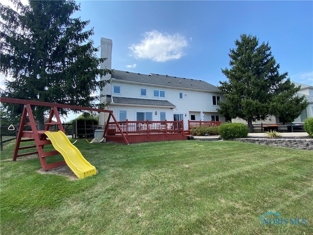 rear view of house with a yard, a deck, and a playground