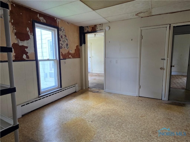 502 N Prospect St, Bowling Green, OH 43402 - spare room featuring a baseboard heating unit, a wainscoted wall, and a drop ceiling