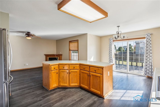 kitchen featuring dark wood-type flooring, decorative light fixtures, ceiling fan with notable chandelier, and stainless steel refrigerator