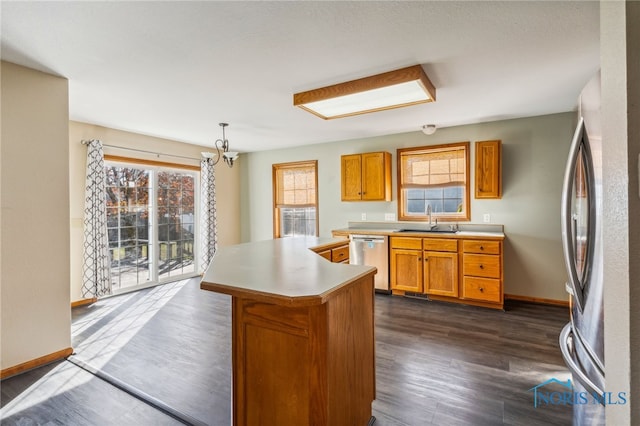 kitchen featuring hanging light fixtures, appliances with stainless steel finishes, dark wood-type flooring, sink, and a center island