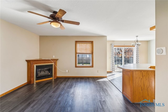 unfurnished living room featuring dark hardwood / wood-style floors and ceiling fan with notable chandelier