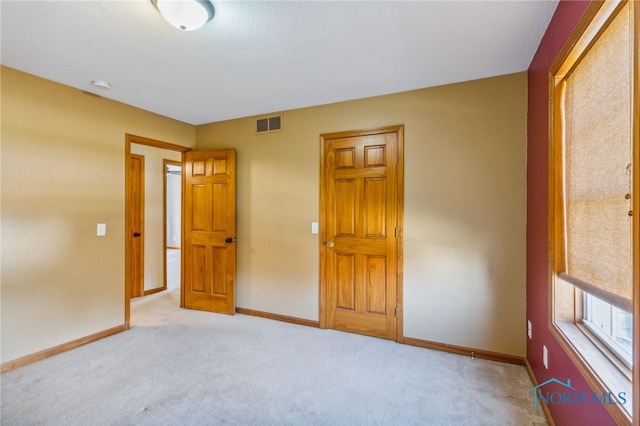 unfurnished bedroom featuring a closet and light colored carpet