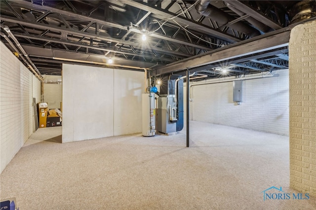 basement featuring electric panel, heating unit, carpet, water heater, and brick wall