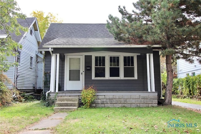 bungalow featuring roof with shingles and a front lawn