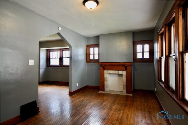 unfurnished living room featuring dark hardwood / wood-style floors and a tile fireplace