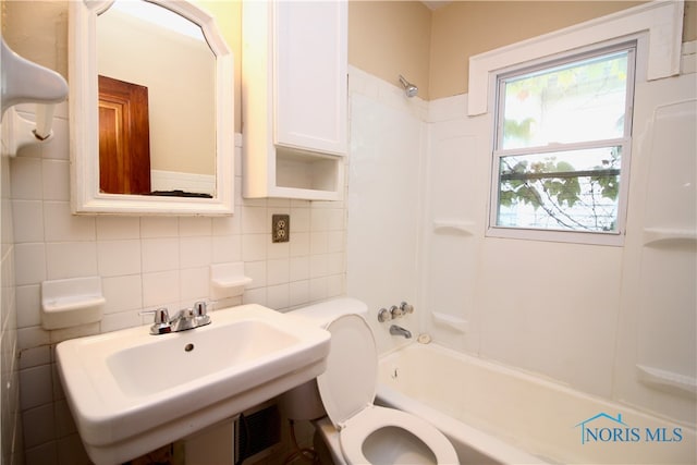 full bathroom with sink, backsplash, toilet, tile walls, and shower / tub combination