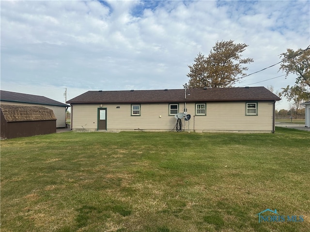 rear view of property featuring a lawn and an outbuilding