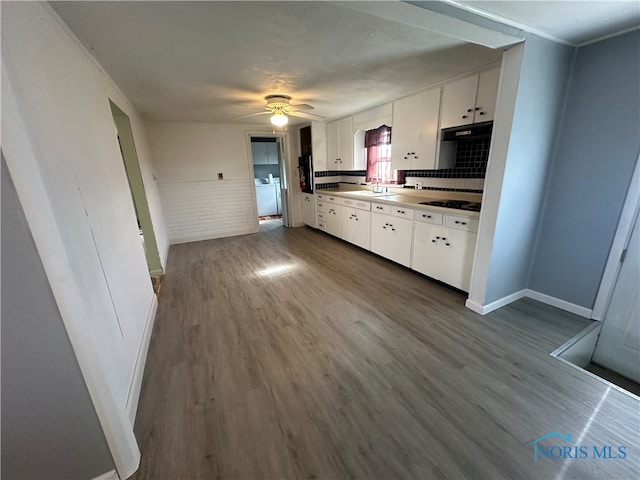 kitchen featuring washer / dryer, backsplash, white cabinetry, ceiling fan, and hardwood / wood-style flooring