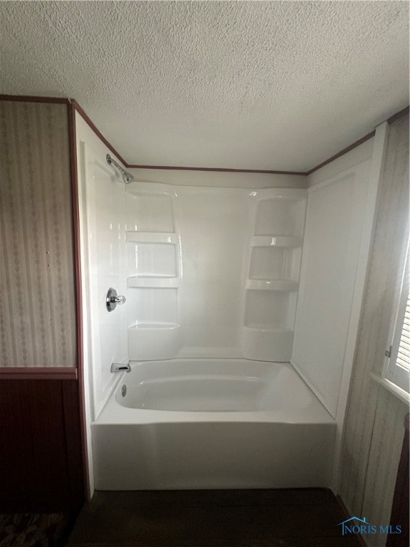 bathroom featuring a textured ceiling, wooden walls, and bathing tub / shower combination