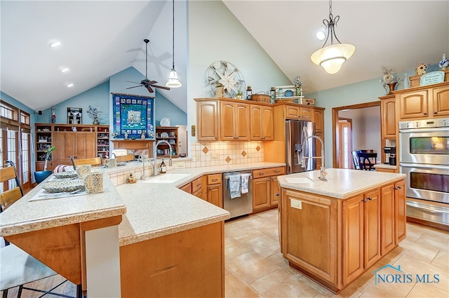 kitchen with a breakfast bar, a center island with sink, hanging light fixtures, appliances with stainless steel finishes, and kitchen peninsula