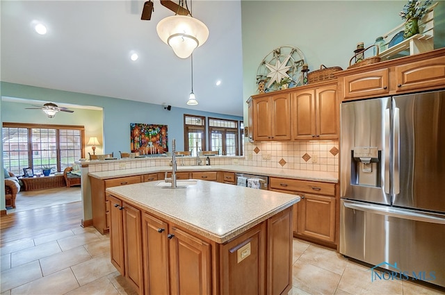 kitchen with kitchen peninsula, stainless steel appliances, sink, pendant lighting, and an island with sink