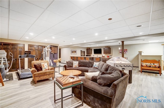 living room with light hardwood / wood-style floors and a drop ceiling