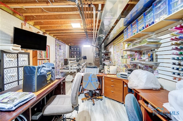 office area with light hardwood / wood-style floors and brick wall