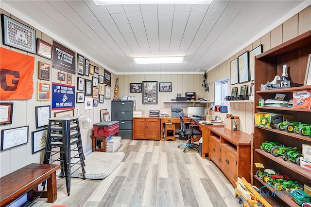 home office featuring light wood-type flooring, ornamental molding, and wood walls