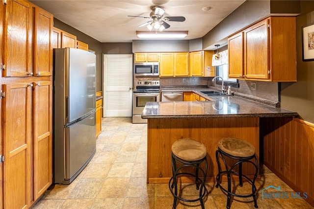 kitchen featuring kitchen peninsula, ceiling fan, a breakfast bar area, sink, and stainless steel appliances