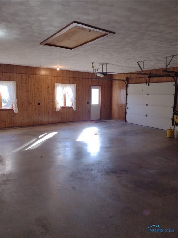 garage featuring a garage door opener and wooden walls