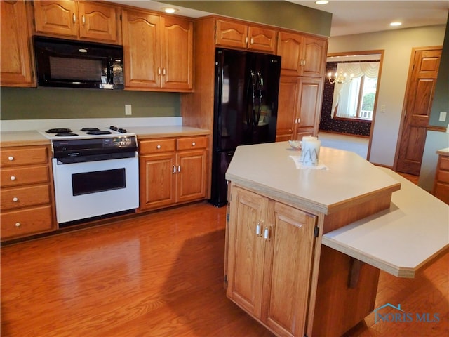 kitchen featuring dark wood-type flooring, black appliances, a chandelier, and a kitchen island