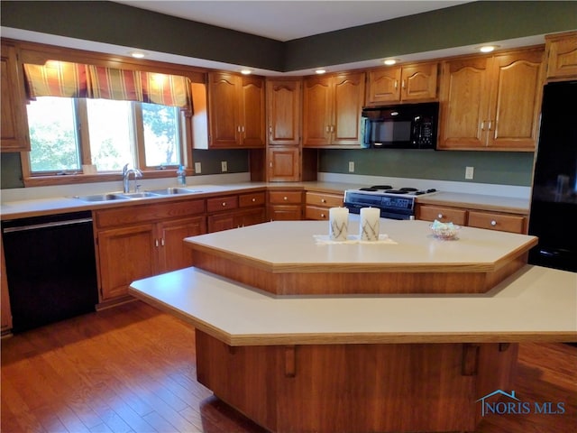 kitchen featuring black appliances, sink, a kitchen island, a kitchen breakfast bar, and dark hardwood / wood-style floors