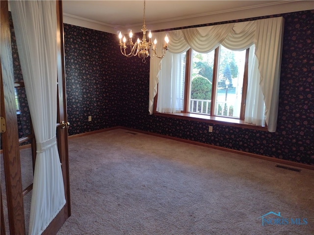 empty room with ornamental molding, carpet floors, and a chandelier