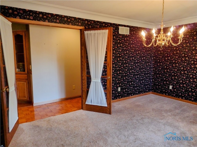 unfurnished room featuring an inviting chandelier, ornamental molding, and carpet