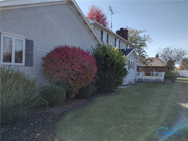 view of side of home featuring a deck and a lawn