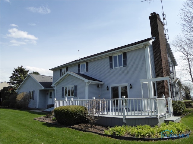 rear view of property with a deck and a yard