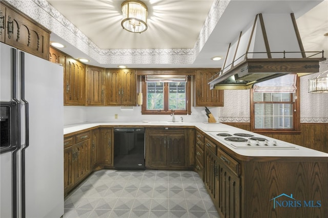 kitchen featuring kitchen peninsula, island exhaust hood, a raised ceiling, sink, and white appliances