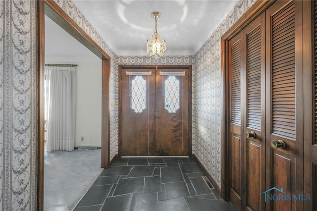 entryway with a notable chandelier and dark colored carpet