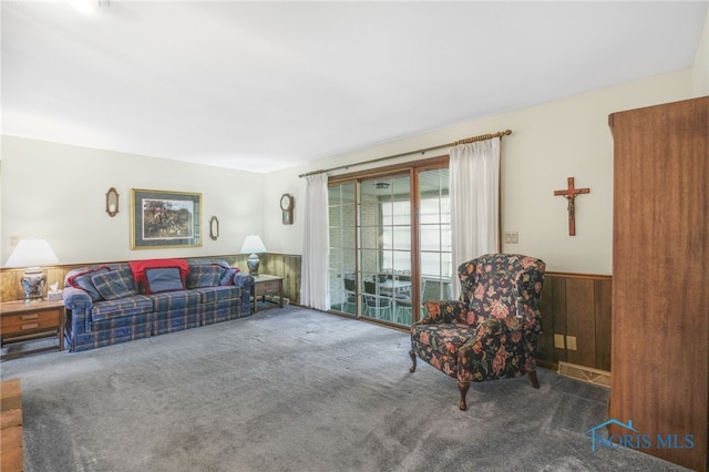 living room featuring dark colored carpet and wood walls