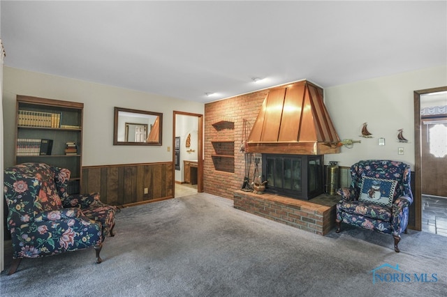 living room with wooden walls, carpet, and a brick fireplace