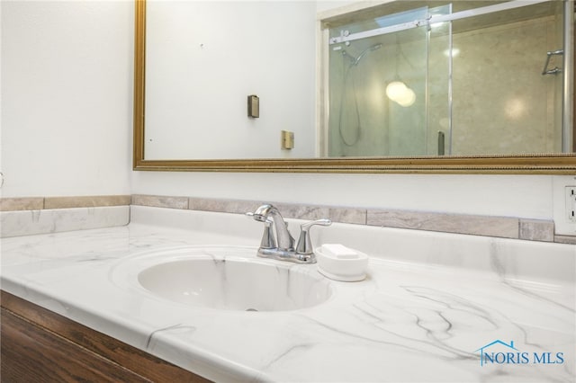 bathroom featuring a shower with door and vanity