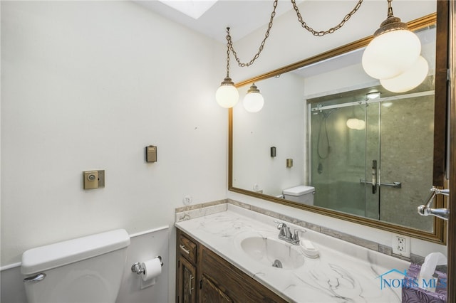 bathroom featuring vanity, toilet, and a shower with door