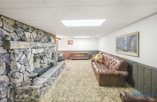 carpeted living room with a drop ceiling and wood walls