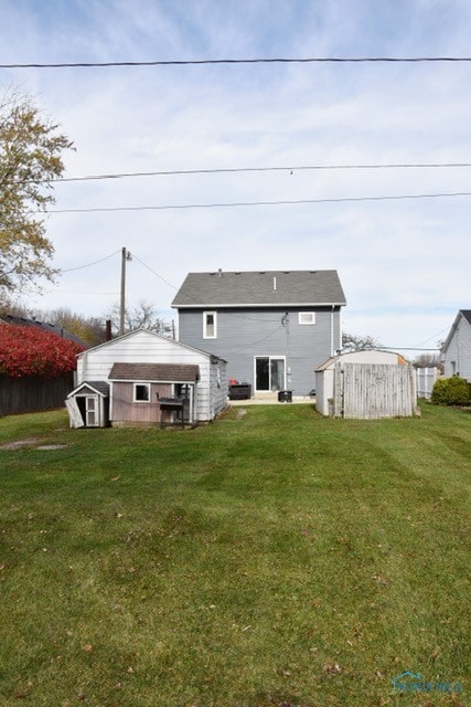 back of house with a storage shed and a lawn