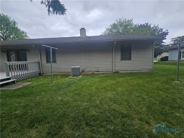 rear view of property featuring a yard and central air condition unit