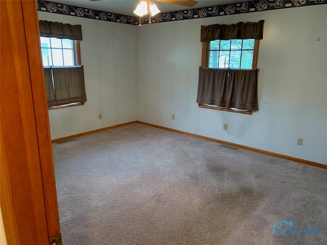 empty room featuring ceiling fan, carpet, and a wealth of natural light