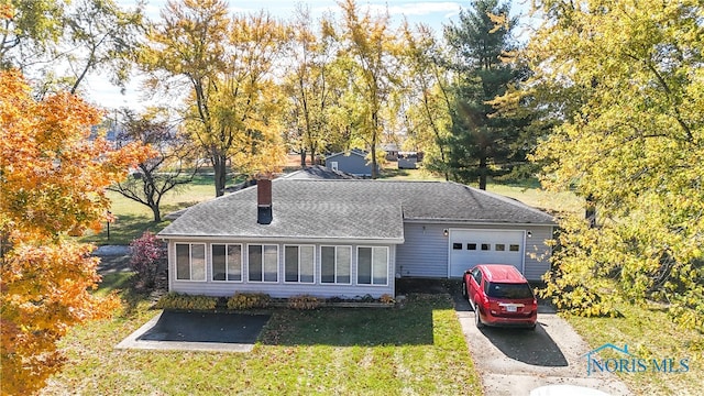 view of front facade featuring a front yard, a garage, and a sunroom